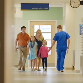 Little girl greeting a doctor as she and her family passes him in the hospital hallway